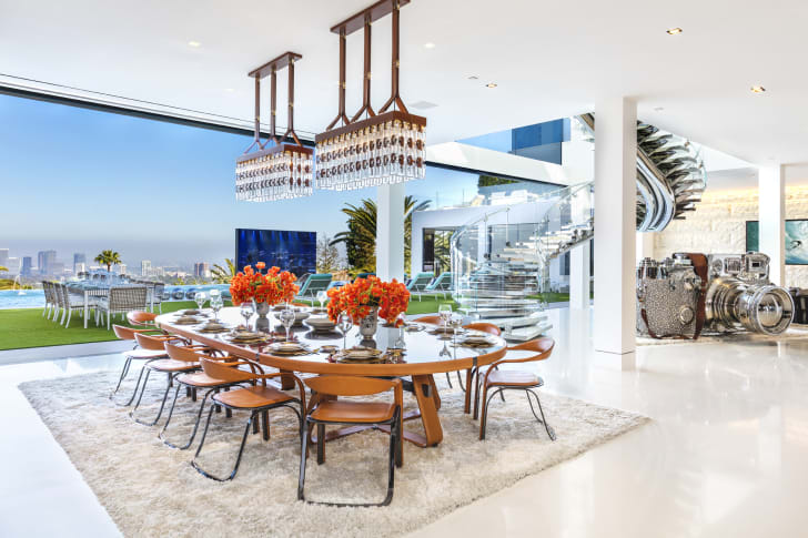 A bright white dining room with floor-to-ceiling windows looking out upon Los Angeles