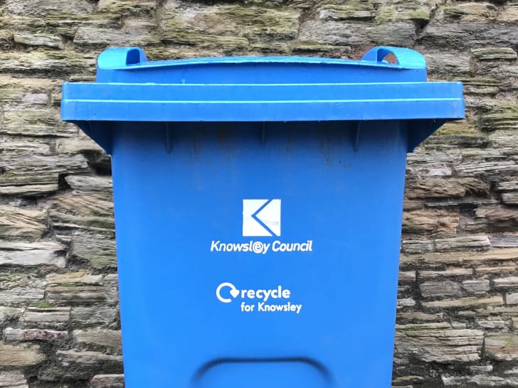A bright blue trash can reads ‘Knowsley Council: Recycle for Knowsley.’