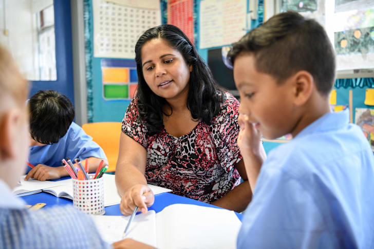 A primary school teacher helping a young boy in the classroom
