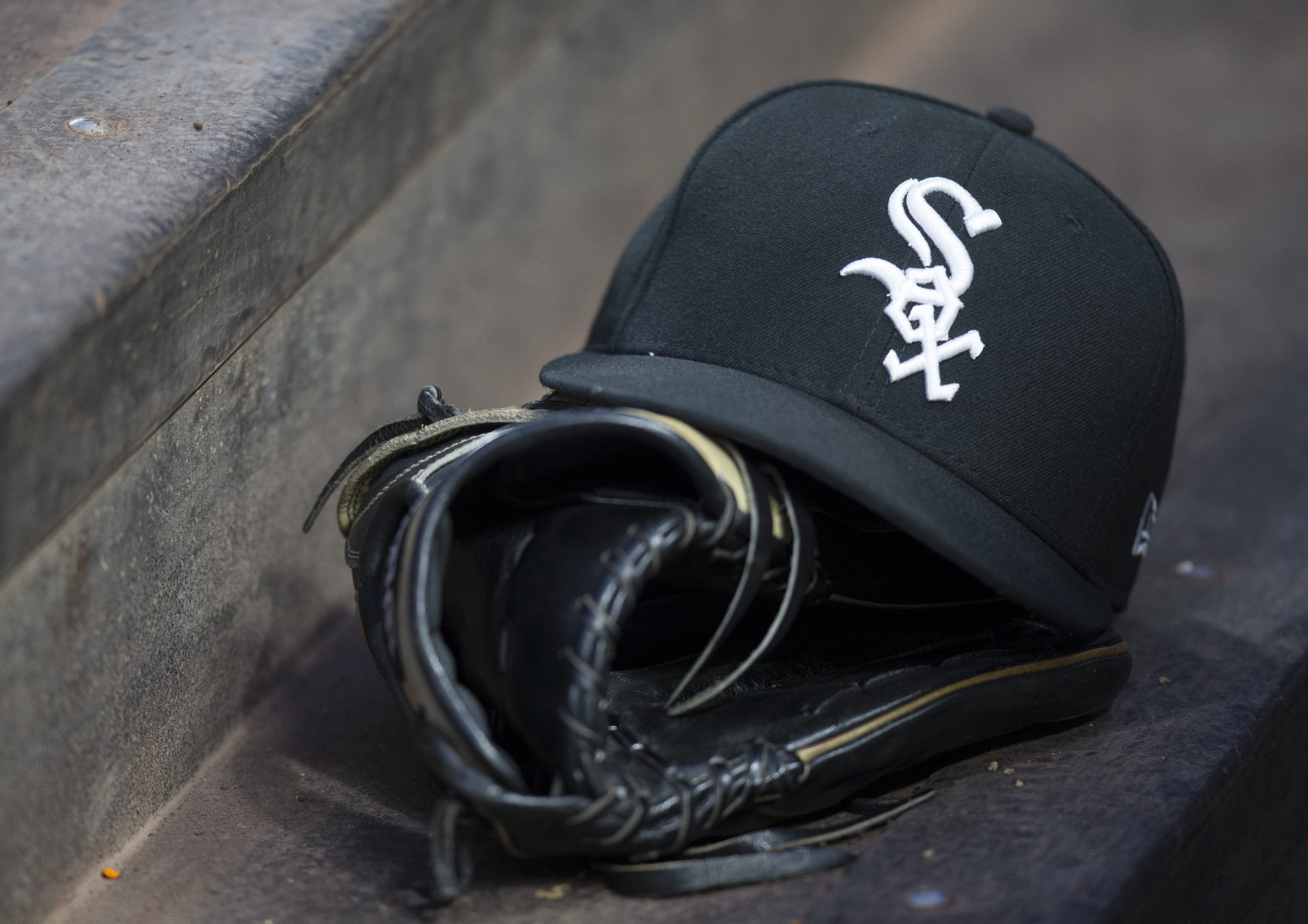 A Chicago White Sox hat and glove are pictured on the steps of the dugout.