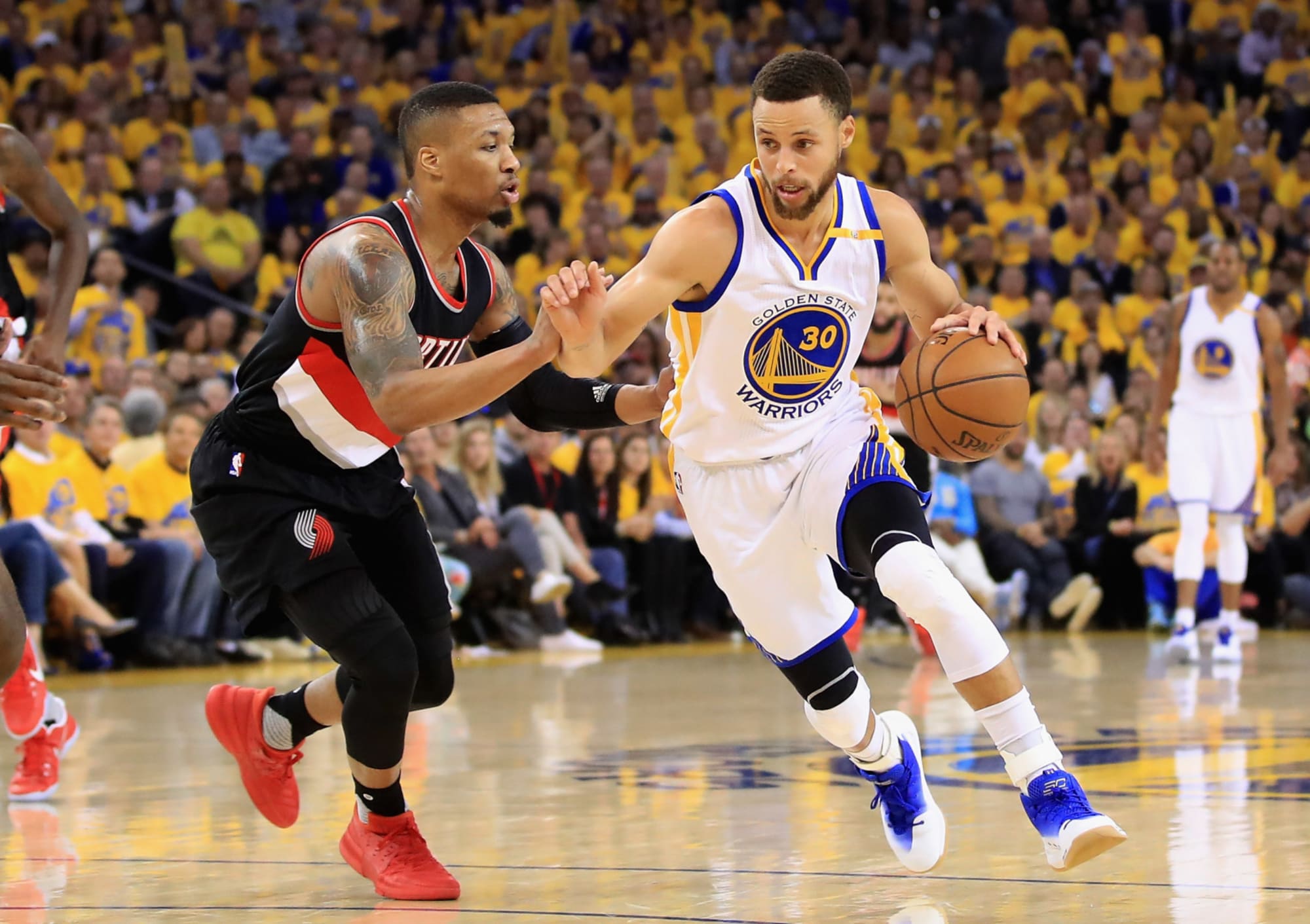 Golden State Warriors guard Stephen Curry (30) steps over Portland Trail  Blazers guard Damian Lillard (0) as he drives to the basket during the  first half of Game 3 of the NBA