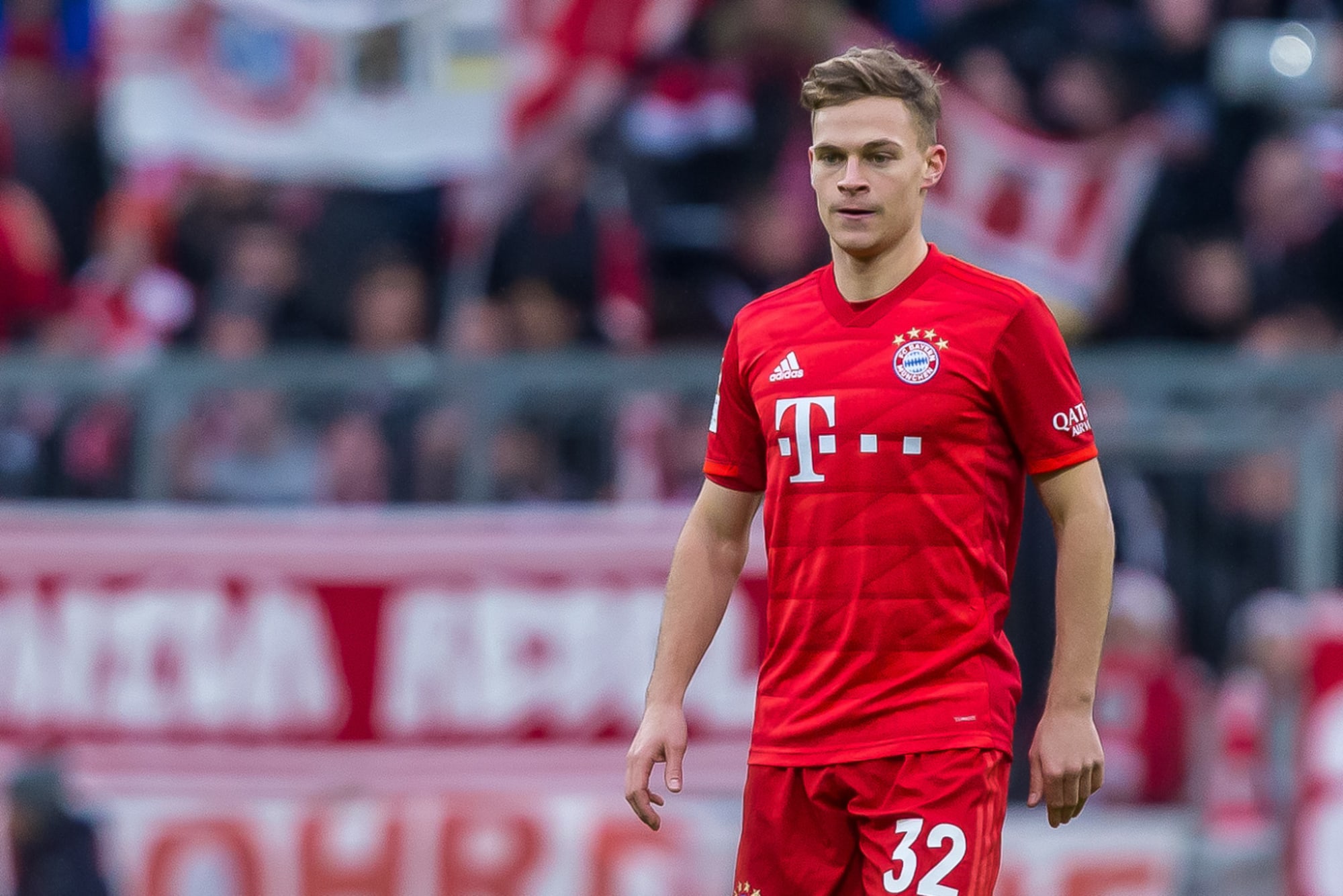  Joshua Kimmich is playing soccer for Bayern Munich, wearing a red jersey with white stripes on the sleeves and red shorts.