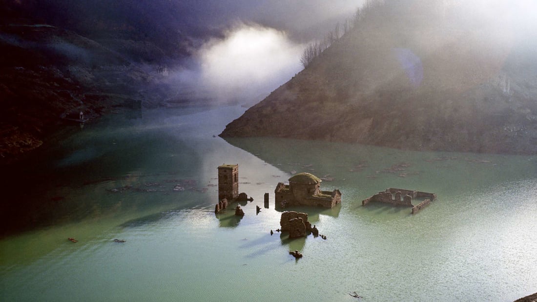 Fabbriche di Careggine espreitando sobre a superfície do lago na Toscana, Itália.