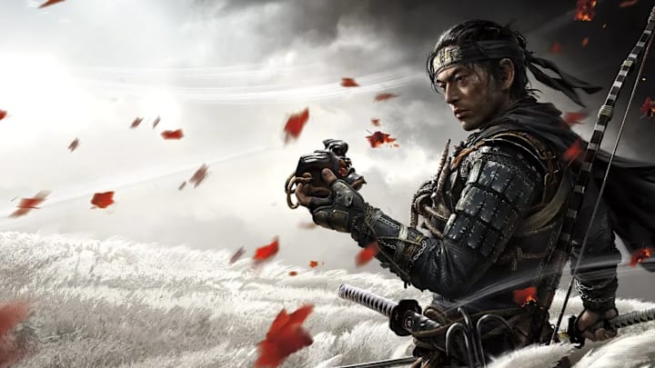 Jin Sakai stands with his mask in his hand in a field of pampas grass in Ghost of Tsushima art. 
