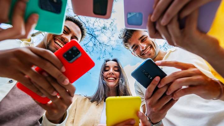 Group of young people seen using phones from below