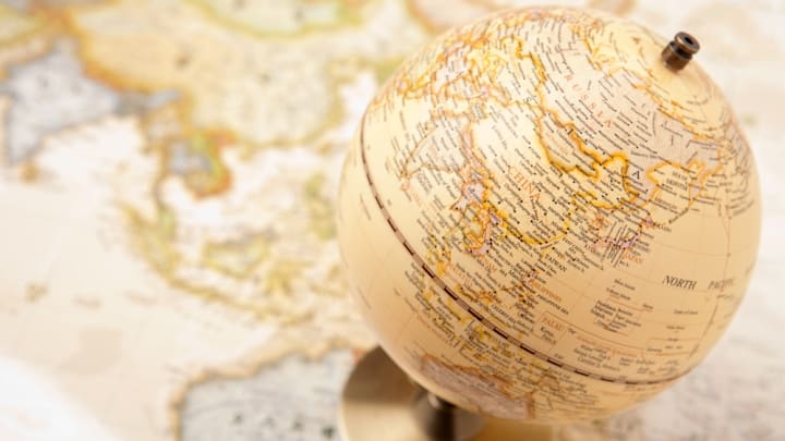 A globe in focus in front of a map