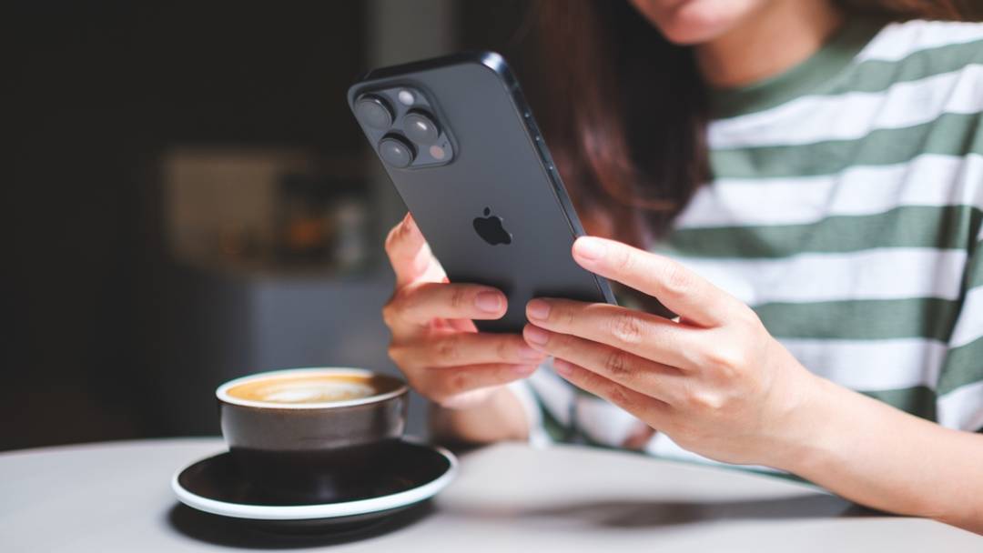 Woman in striped shirt with latte using black iPhone Woman in striped shirt with latte using black iPhone