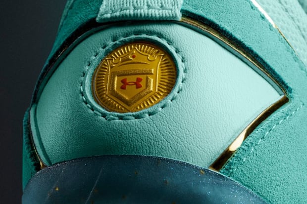 Under Armour logo on teal baseball cleats.