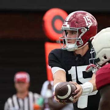 Ty Simpson (15) hands the football off to Jam Miller (26).