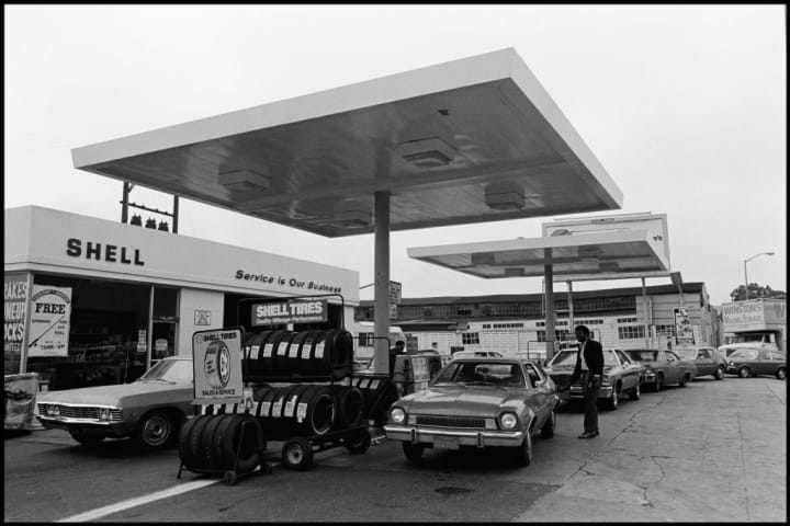 A line of cars at a gas station during the 1970s.