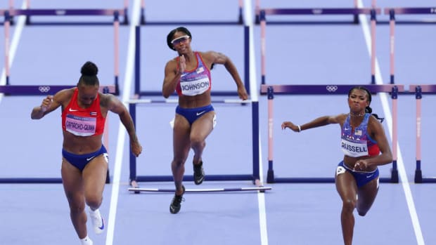 U.S. hurdler Masai Russell (right) leans to the finish line in the 100-meter hurdles at the Paris Olympics.