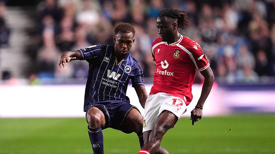 Millwall's Zak Sturge (left) and Wrexham's Issa Kabore battle for the ball.
