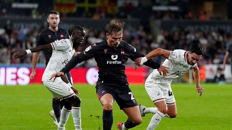 Wrexham's Callum Doyle (centre) battles for the ball with Swansea City's Moussa Yeo (left) and Stephen Eustaquio (right).