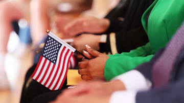A person holds an American flag during a naturalization ceremony on the ship ‘Wavertree’ in New York City. The 20 candidates were from 17 countries and 5 of the candidates were current or former members of the U.S. military.