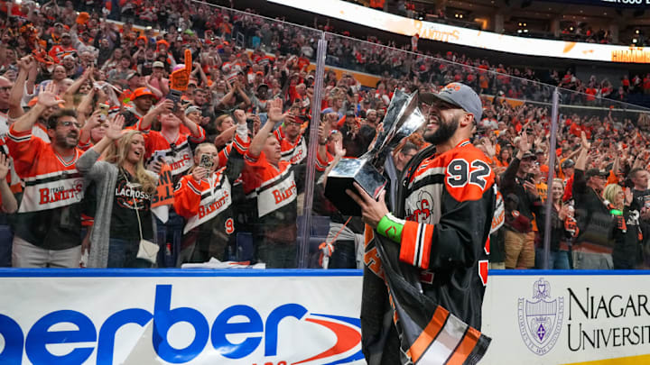 Dhane Smith of the Buffalo Bandits carries the trophy after winning the NLL Championship in 2023.
