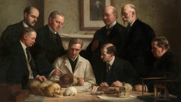 A portrait of the scientists who found and examined the Piltdown Man skull (accompanied by a picture of Charles Darwin on the wall).