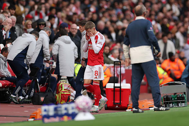 Martin Ødegaard holds his hands to face in dismay after hobbling off injured.