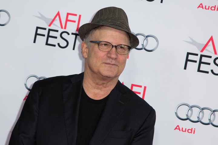 Albert Brooks wearing a fedora on a red carpet in 2015