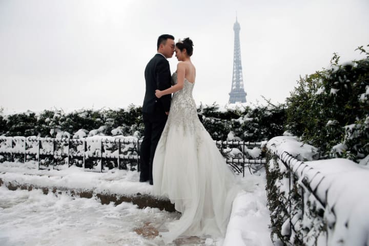 photo of a bride and groom posing in the snow, with the Eiffel Tower in the background