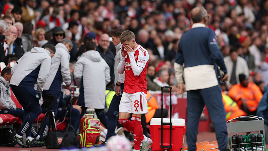 Martin Ødegaard holds his hands to face in dismay after hobbling off injured.