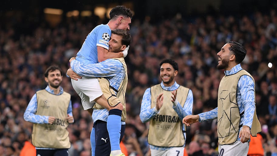 Phil Foden embraced by Man City teammates.