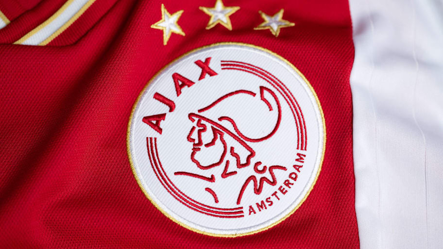 The badge of Ajax on a red and white home shir