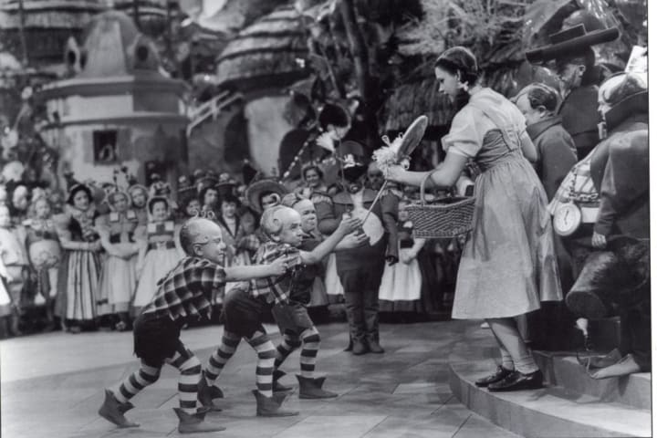 Jerry Maren presents Judy Garland with a lollipop in the film "The Wizard of Oz."