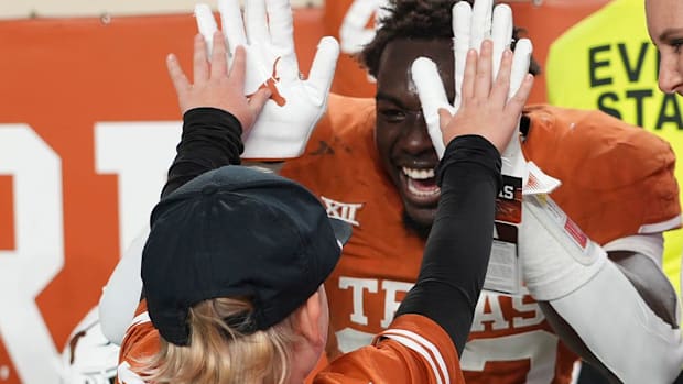 Texas linebacker David Gbenda (33) high-fives Beau Rutherford, 6, following the game against Texas Tech at home in Nov. 2023.