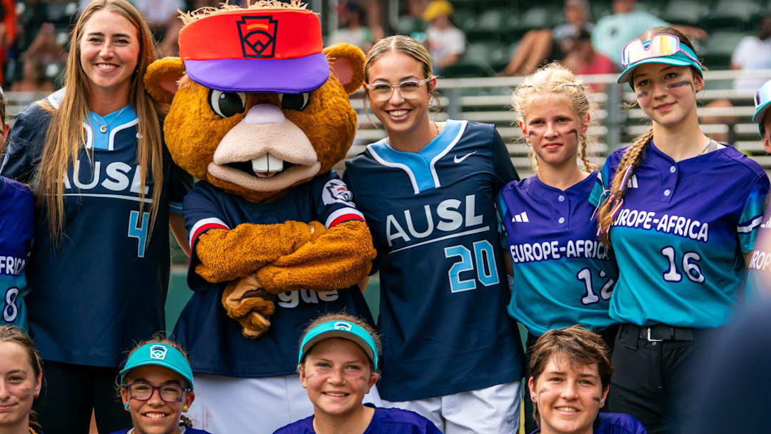 AUSL pitchers Georgina Corrick (4) and Sam Landry (20) pose for a picture with Europe-Africa's team and Little League Softball World Series mascot ahead of Tuesday, August 5 games. AUSL pitchers Georgina Corrick (4) and Sam Landry (20) pose for a picture with Europe-Africa's team and Little League Softball World Series mascot ahead of Tuesday, August 5 games.