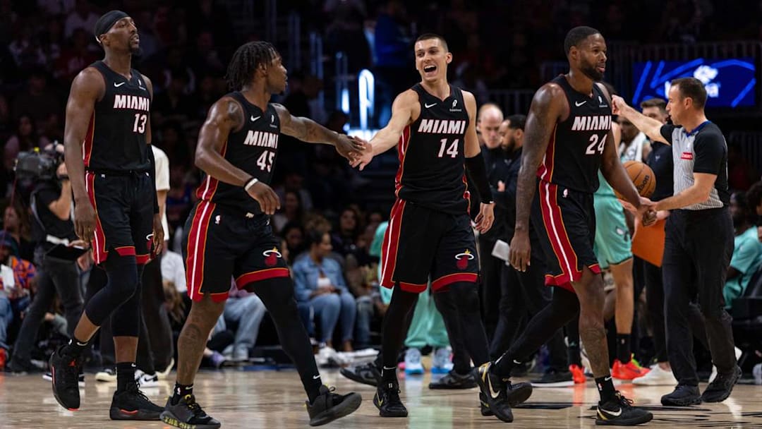 Miami Heat guard Tyler Herro (14) reacts with guard Davion Mitchell (45), Bam Adebayo (13) and Haywood Highsmith (24) the second half of an NBA game against the Charlotte Hornets at Kaseya Center on March 21, 2025, in Miami. 