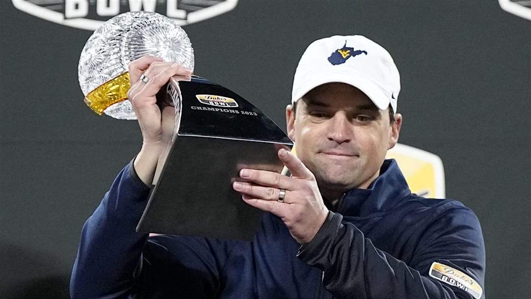 Ex-WVU HC Neal Brown holds up the Duke's Mayo Bowl Trophy.