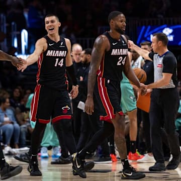 Miami Heat guard Tyler Herro (14) reacts with guard Davion Mitchell (45), Bam Adebayo (13) and Haywood Highsmith (24) the second half of an NBA game against the Charlotte Hornets at Kaseya Center on March 21, 2025, in Miami. 