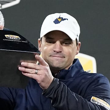 Ex-WVU HC Neal Brown holds up the Duke's Mayo Bowl Trophy.