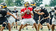Sione Kaho looks for a receiver at a football camp.