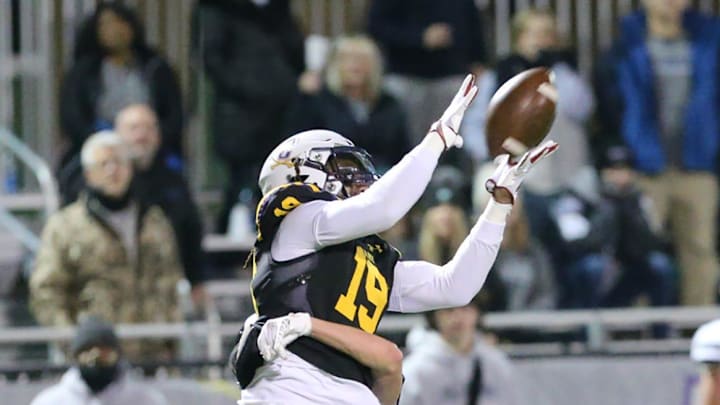 Fellowship Christian's Josh Milhollin hits Calvary's Edward Coleman as he attempts to make a catch during the 4th quarter of Friday night's playoff game.