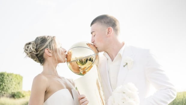 Former Oregon Duck Payton Pritchard and wife Emma MacDonald share a kiss with the Larry O'Brien trophy at their wedding in Ma