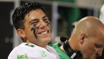 Dayton Raiola smiling on the sideline at his high school football game 