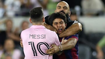 Yassine Chueko apartando a un aficionado que ingresó al campo para tomarse una foto con Lionel Messi