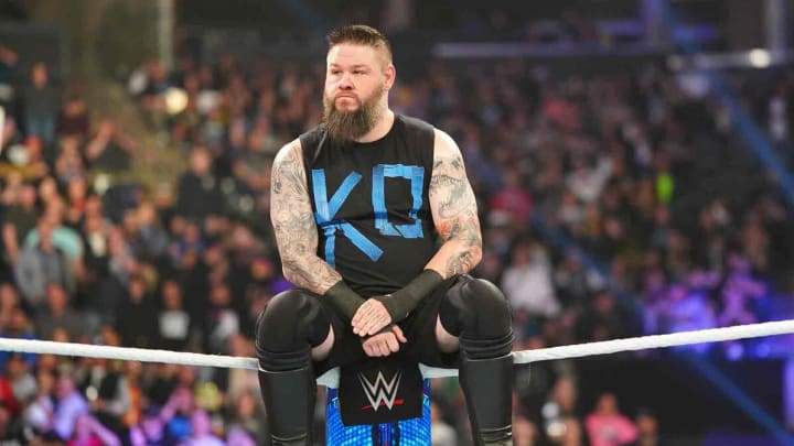 Kevin Owens sits on the middle rope while staring down his foe. Kevin Owens sits on the middle rope while staring down his foe.
