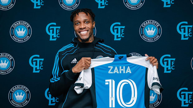 Wilfred Zaha holds a Charlotte FC kit. 