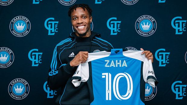 Wilfred Zaha holds a Charlotte FC kit. 