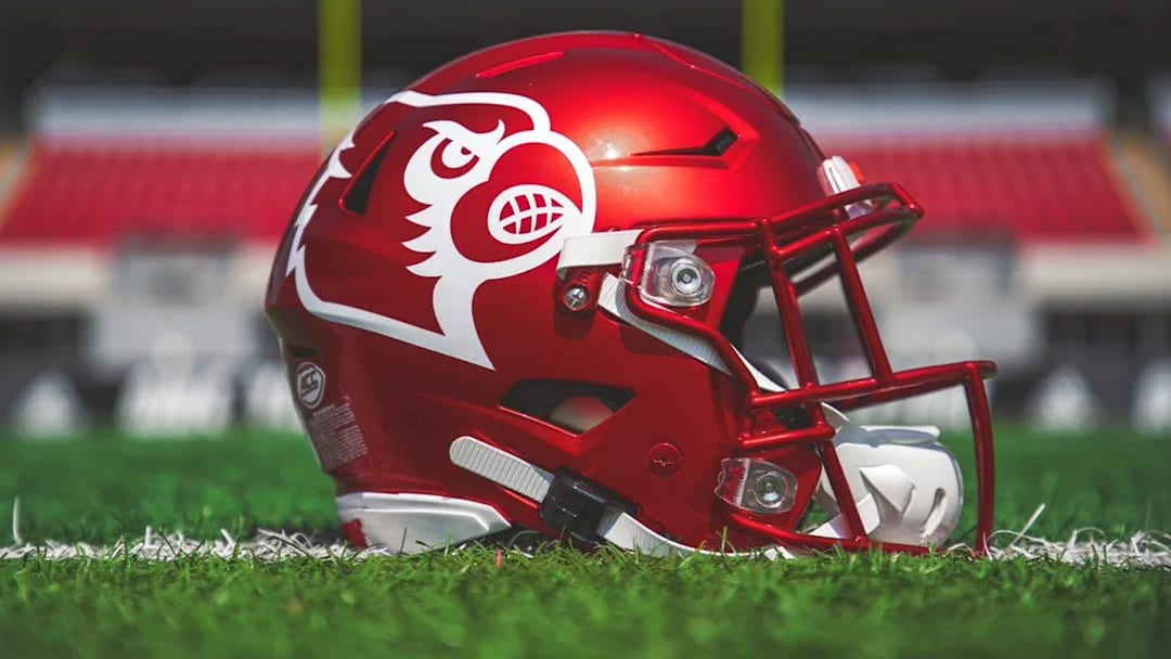 A cherry red football helmet with the white-outlined Louisville logo.