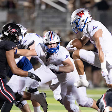 Westlake hurdles through the Lake Travis defense in a 2023 high school football game in Texas.