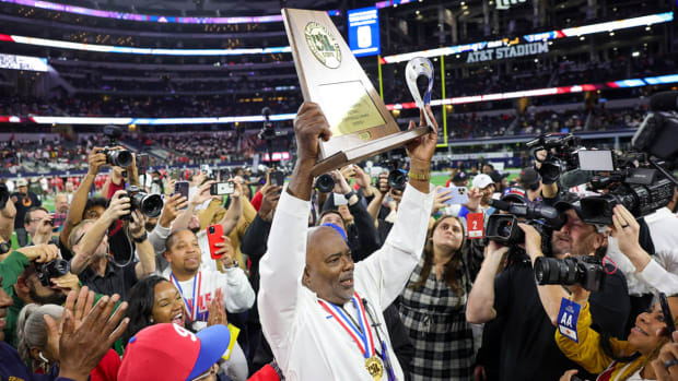 Duncanville (Texas) coach Reginald Sample holds up the UIL 6A Division I 2023 state championship trophy.