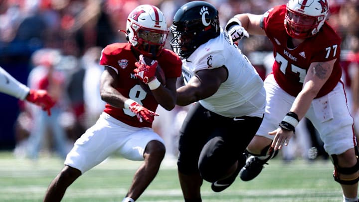 Miami Redhawks running back Kevin Davis (8) runs by Cincinnati Bearcats defensive tackle Dontay Corleone (2) in the first quarter of the College Football game at Yager Stadium in Cincinnati on Saturday, Sept. 14, 2024.