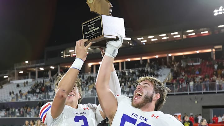 Ryder Lyons (left) and Lucas Hardeman celebrate by hoisting the state championship trophy at Saddleback College from the 2023 State Division 1-A title game. Saddleback has been secured for the fourth straight year to host tentative the top five divisions of the 15-game State Bowl Championships. 