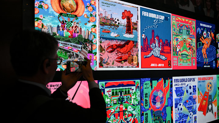 Una persona fotografía un muro con diferentes artes de diversas ciudades sedes de la próxima Copa del Mundo de Norteamérica, a celebrarse el año próximo en EUU, Canadá y México.