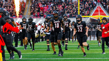 Louisville players running onto the field of L&N Stadium during pregame.