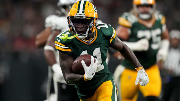 Packers wide receiver Jayden Reed (green jersey; yellow helmet) looks for room to run after a catch. 