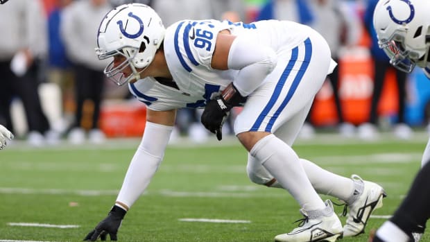 Colts defensive tackle Taven Bryan (all-white uniform with blue trim) sets up before a snap on defense. 